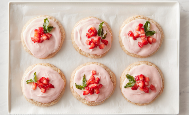 Six round frosted cookies topped with chopped strawberries